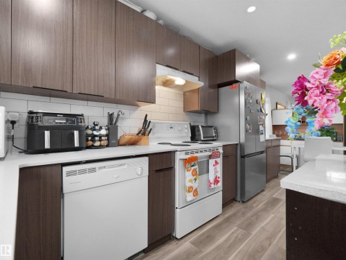 Kitchen featuring wood-finish cabinetry, white countertops, subway tile backsplash, and light wood-finish flooring - 15511 45 Street Nw, Edmonton, AB 