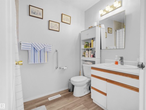 White vanity with wood-finish accents, integrated sink, and brushed chrome faucet - 15511 45 Street Nw, Edmonton, AB 
