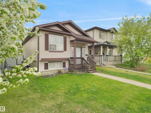 Two-story dwelling featuring a covered front porch, light-toned siding, and brown exterior trim - 15511 45 Street Nw, Edmonton, AB 