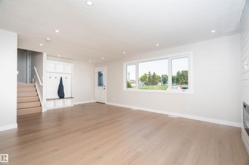 Spacious living area featuring wood-finish flooring, recessed lighting, and a large multi-pane window - 904 Knottwood S Nw, Edmonton, AB 