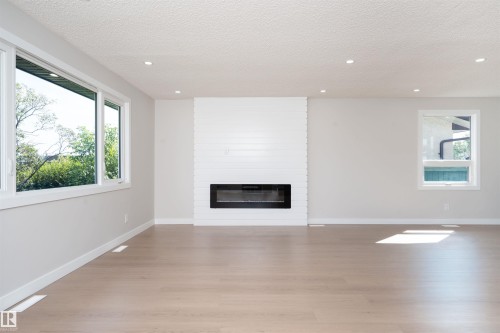 Modern electric fireplace with a white shiplap surround, recessed lighting, and light wood-finish flooring - 904 Knottwood S Nw, Edmonton, AB 