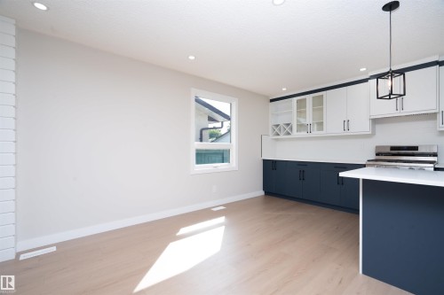 Kitchen featuring two-tone cabinetry, stainless steel range, and a breakfast bar - 904 Knottwood S Nw, Edmonton, AB 