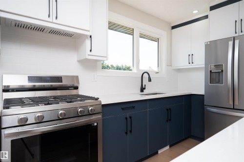 Stainless steel appliances, two-tone cabinetry, white countertops, subway tile backsplash, and a matte black faucet - 904 Knottwood S Nw, Edmonton, AB 