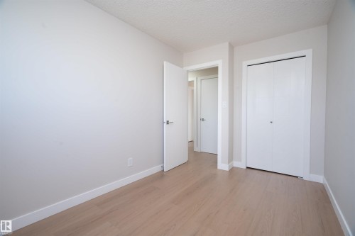 Light wood-finish flooring, white walls, white bi-fold closet doors, and white interior doors with contemporary hardware - 904 Knottwood S Nw, Edmonton, AB 