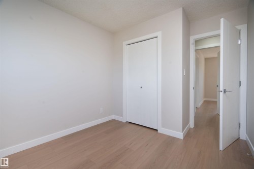 Light-toned wood-finish flooring throughout, white baseboards, and a bi-fold closet with a silver knob - 904 Knottwood S Nw, Edmonton, AB 