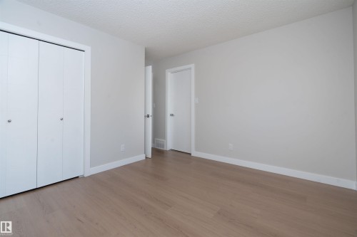 Light wood-finish flooring with white trim, neutral wall paint, and closet with bi-fold doors - 904 Knottwood S Nw, Edmonton, AB 