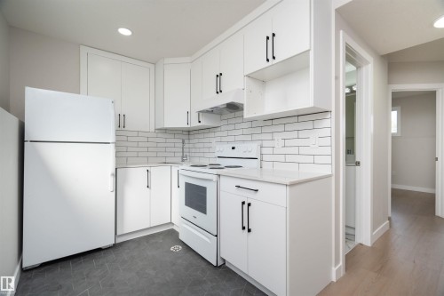 White kitchen cabinetry with black hardware, white subway tile backsplash, white countertop, and recessed ceiling lighting - 904 Knottwood S Nw, Edmonton, AB 