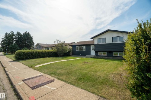 Two-tone siding exterior, front yard with mature shrubbery, expansive green lawn, and a concrete sidewalk - 904 Knottwood S Nw, Edmonton, AB 
