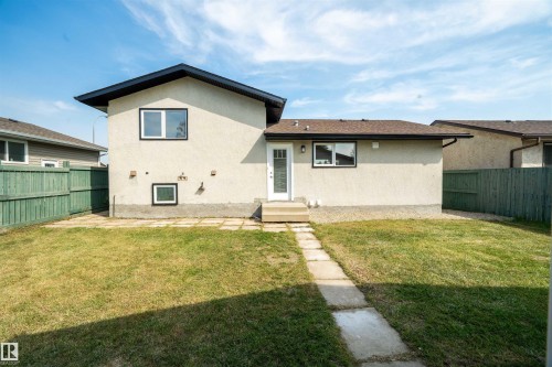 Grassed backyard with a concrete paver pathway and a back entrance with exterior steps - 904 Knottwood S Nw, Edmonton, AB 