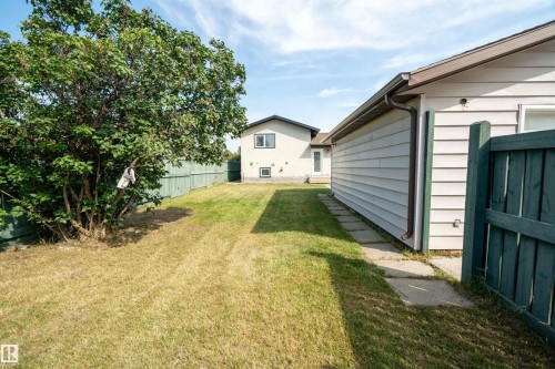 Expansive yard featuring a manicured lawn, established tree, wood fencing, and concrete stepping stones - 904 Knottwood S Nw, Edmonton, AB 