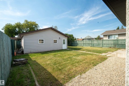 Expansive fenced yard featuring a detached garage with two windows, a side entry door, and a gravel area - 904 Knottwood S Nw, Edmonton, AB 