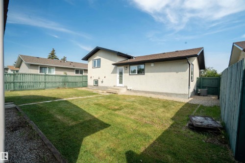 Expansive backyard featuring a manicured lawn, gravel perimeter, and green fencing - 904 Knottwood S Nw, Edmonton, AB 