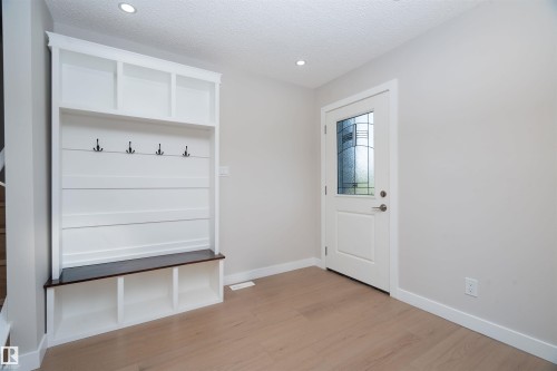Built-in hall tree with storage, decorative glass panel entry door, recessed lighting, and wood-finish flooring - 904 Knottwood S Nw, Edmonton, AB 