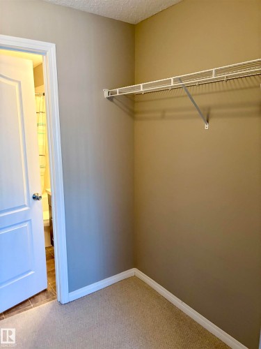 Wall-to-wall carpeting with neutral wall tones, white trim, and a white wire shelving unit - #1304 9363 Simpson Dr Nw, Edmonton, AB 