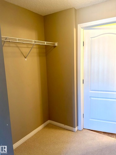 Neutral tone wall finish, white wire shelving, light-toned carpeting, white trim, and a paneled interior door - #1304 9363 Simpson Dr Nw, Edmonton, AB 
