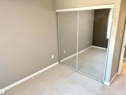 Neutral-toned carpeting, mirrored sliding closet doors, and light gray wall finishes - #1304 9363 Simpson Dr Nw, Edmonton, AB 
