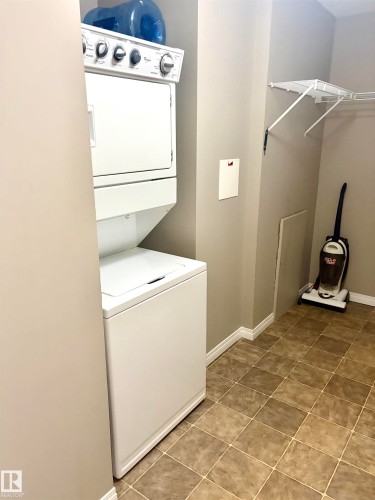Stacked washer and dryer unit, tiled flooring, and wire shelving - #1304 9363 Simpson Dr Nw, Edmonton, AB 