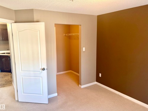 Carpeted room with a built-in closet featuring a clothes rod and shelving - #1304 9363 Simpson Dr Nw, Edmonton, AB 