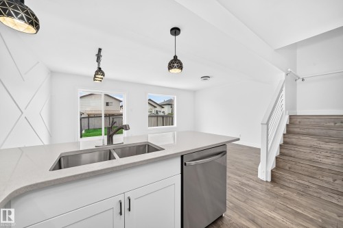Kitchen island with a double basin stainless steel sink and integrated stainless steel dishwasher - 13005 162A Avenue Nw, Edmonton, AB - Indoor Photo Showing Kitchen With Double Sink