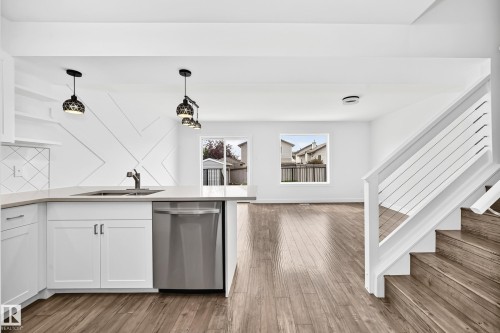 Modern kitchen featuring white cabinetry, light-toned countertops, and stainless steel appliances - 13005 162A Avenue Nw, Edmonton, AB - Indoor