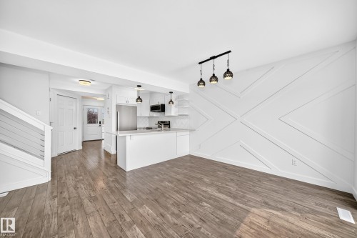 Open-concept living area featuring wood-finish flooring, a contemporary accent wall, and recessed lighting - 13005 162A Avenue Nw, Edmonton, AB - Indoor