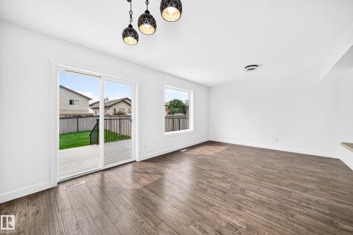 Spacious room featuring wood-finish flooring, white walls, and a contemporary three-light pendant fixture - 13005 162A Avenue Nw, Edmonton, AB - Indoor Photo Showing Other Room