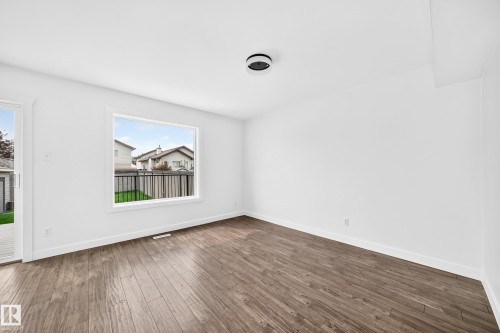 Bright interior space featuring wood-finish flooring, white walls, and a contemporary flush-mount ceiling light - 13005 162A Avenue Nw, Edmonton, AB - Indoor Photo Showing Other Room