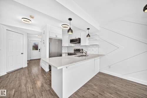 Contemporary kitchen featuring a white quartz-finish island, stainless steel appliances, and white shaker cabinetry - 13005 162A Avenue Nw, Edmonton, AB - Indoor Photo Showing Kitchen