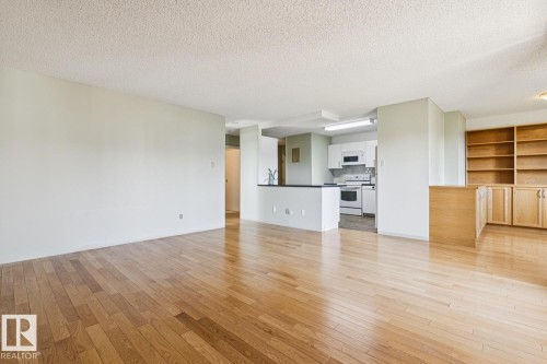 Light wood-finish flooring throughout, built-in shelving, built-in cabinetry, and white kitchen appliances - #905 9929 113 St Nw, Edmonton, AB 