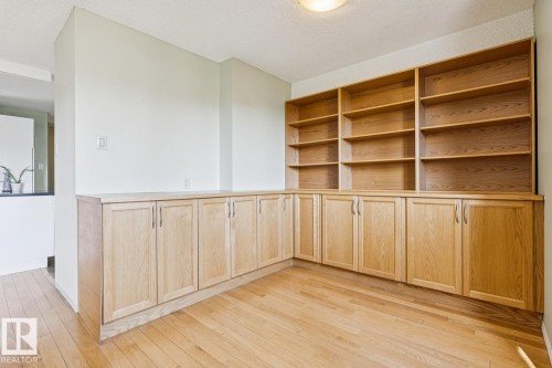 Built-in wood cabinetry with integrated shelving, wood-finish flooring, and white painted walls - #905 9929 113 St Nw, Edmonton, AB 