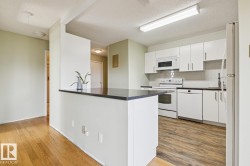 Kitchen featuring white cabinetry, dark countertops, white appliances, and a tile backsplash - 