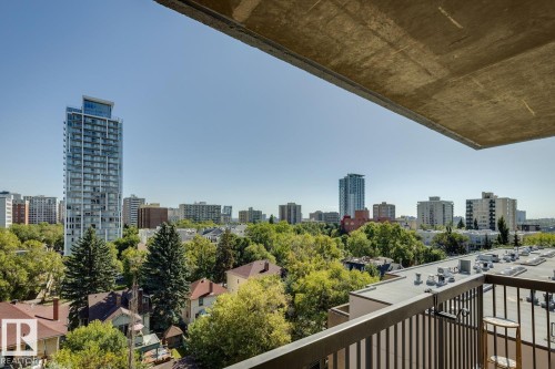 Balcony with black metal railing overlooking a cityscape with mature trees and diverse architectural styles - #905 9929 113 St Nw, Edmonton, AB 