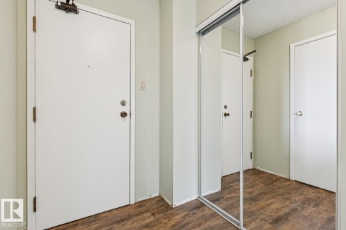 Wood-finish flooring with white interior doors and a full-length mirrored closet door - #905 9929 113 St Nw, Edmonton, AB 
