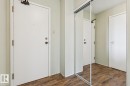 Wood-finish flooring with white interior doors and a full-length mirrored closet door - #905 9929 113 St Nw, Edmonton, AB 