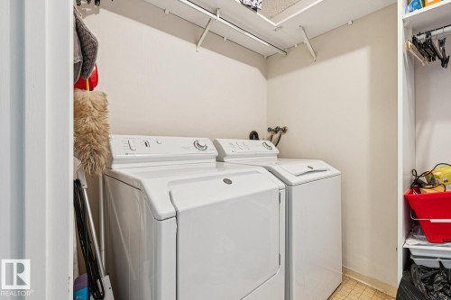 Laundry area featuring a top-load washer and front-load dryer, wall-mounted shelving, and tiled flooring - #905 9929 113 St Nw, Edmonton, AB 