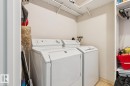 Laundry area featuring a top-load washer and front-load dryer, wall-mounted shelving, and tiled flooring - #905 9929 113 St Nw, Edmonton, AB 