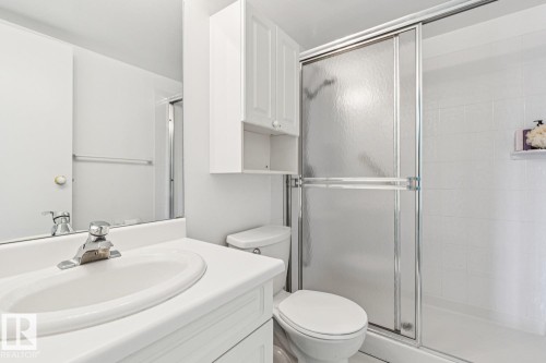 Bathroom featuring a single vanity, a chrome faucet, a wall-mounted medicine cabinet, and a shower with sliding glass doors - #905 9929 113 St Nw, Edmonton, AB 