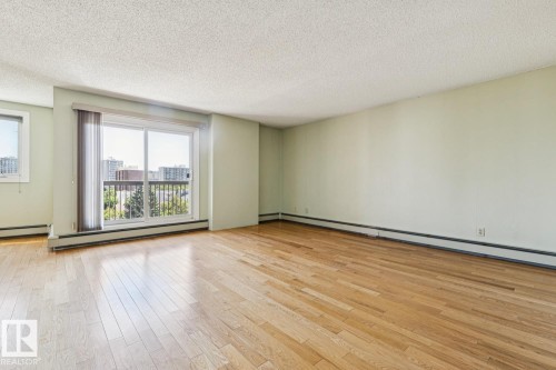Hardwood flooring throughout, large sliding glass door with balcony access, and two windows providing ample natural illumination - #905 9929 113 St Nw, Edmonton, AB 