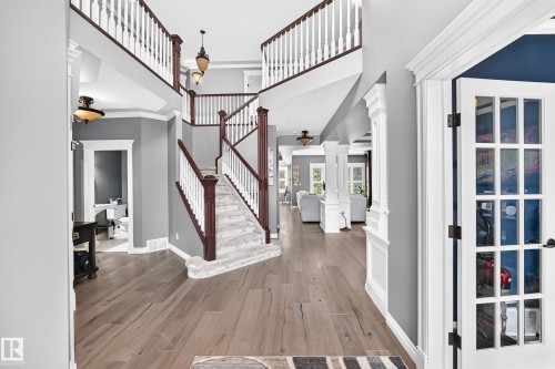 , grand staircase with white balusters and dark wood newel posts, recessed lighting, and white French doors - 417 Caldwell Place Nw, Edmonton, AB 