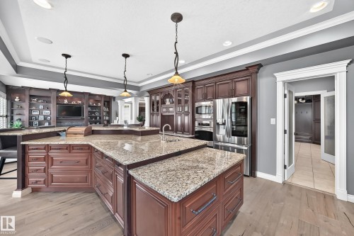 Expansive kitchen island with granite countertops, rich wood cabinetry, stainless steel appliances, and integrated ceiling lighting - 417 Caldwell Place Nw, Edmonton, AB 