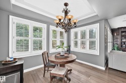 Recessed ceiling with crown molding, decorative chandelier, white plantation shutters, built-in shelving - 