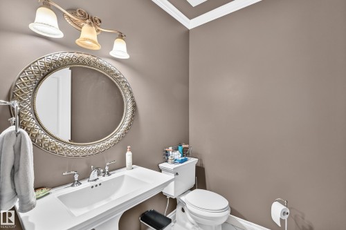 Pedestal sink with chrome fixtures and an oval framed mirror - 417 Caldwell Place Nw, Edmonton, AB 