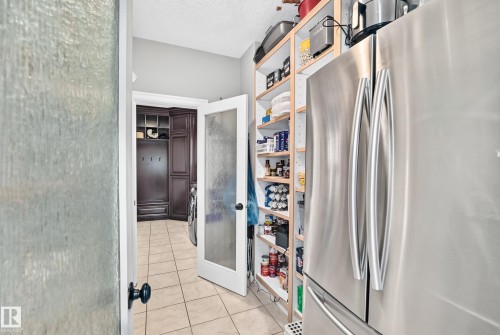 Stainless steel refrigerator, built-in open shelving, and a glass-paneled door - 417 Caldwell Place Nw, Edmonton, AB 