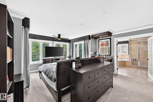 Carpeted room with multiple windows, a ceiling fan, and a built-in bookshelf - 417 Caldwell Place Nw, Edmonton, AB 