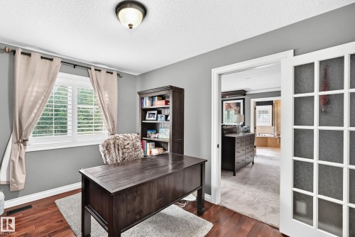 Wood-finish flooring, white window shutters, ceiling-mounted light fixture, and French doors with frosted glass panels - 417 Caldwell Place Nw, Edmonton, AB 