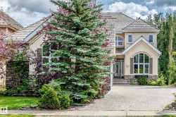 Elegant two-story residence featuring a cream and stone exterior with architectural detailing, arched entryway, and multi-pane windows - 