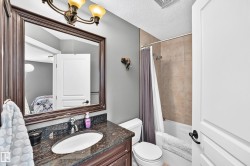 Bathroom featuring a single vanity with stone countertop, mounted sink, and an overhead bronze-tone light fixture - 