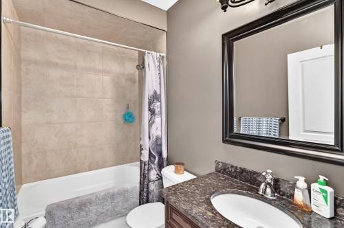 Bathroom featuring a vanity with a dark speckled countertop, an undermount sink, and a framed mirror - 417 Caldwell Place Nw, Edmonton, AB 