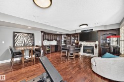 featuring a built-in wet bar with sink and cabinetry, built-in entertainment center with shelving, and a gas fireplace with stone surround - 