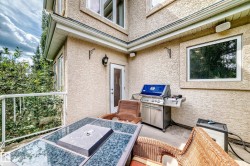 Outdoor patio area with textured stucco exterior, white railing, and exterior lighting fixtures - 